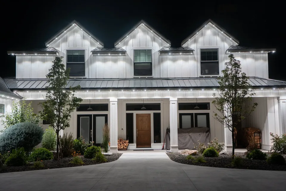 Cool white on the three gables of a white farmhouse, with the covered porch lit underneath.