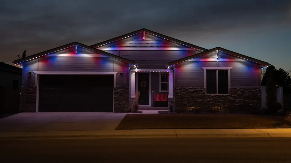 A three gable ranch at dusk, the roofline run set to red, white and blue.