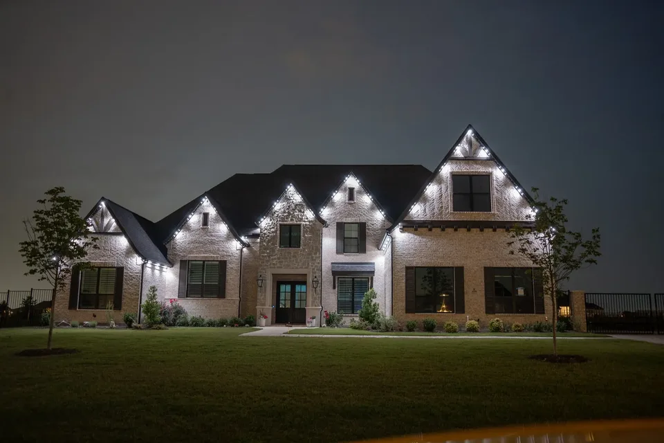 A white brick house at night with every gable and eave outlined in crisp bright white light.