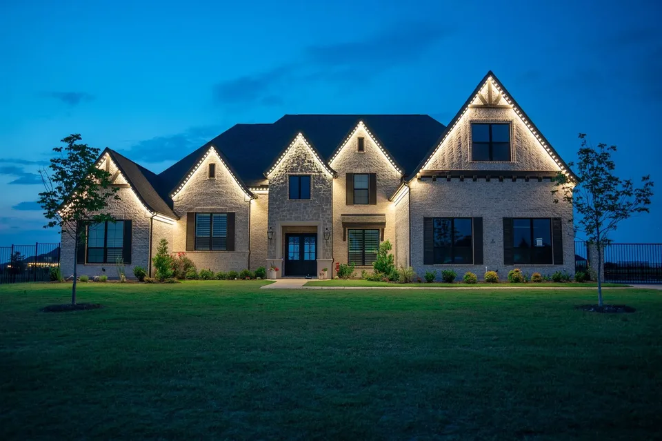 A house with five gables at blue hour, every roof rake and eave traced in white against a deep blue sky.