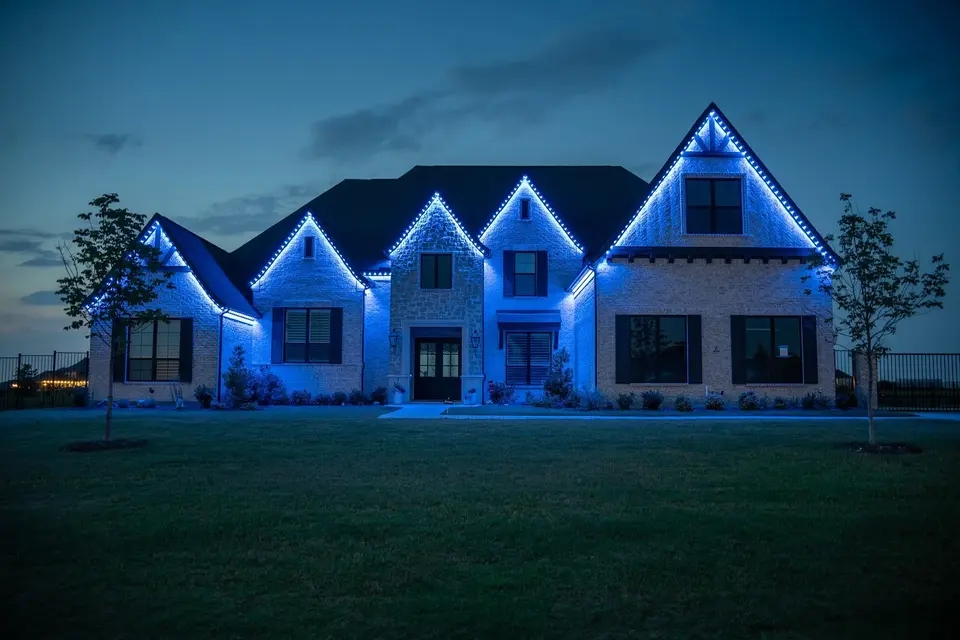A large house at dusk with five gables, every roofline run lit a single cool blue against a fading sky.