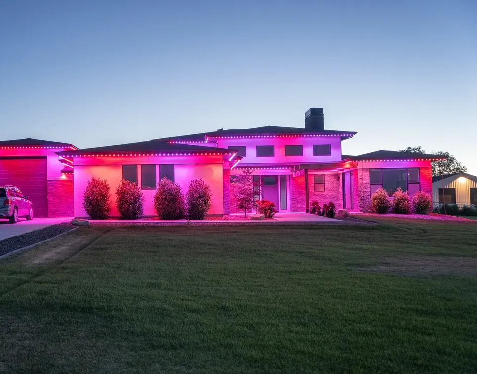 The same house in magenta and pink along the whole roofline at dusk.