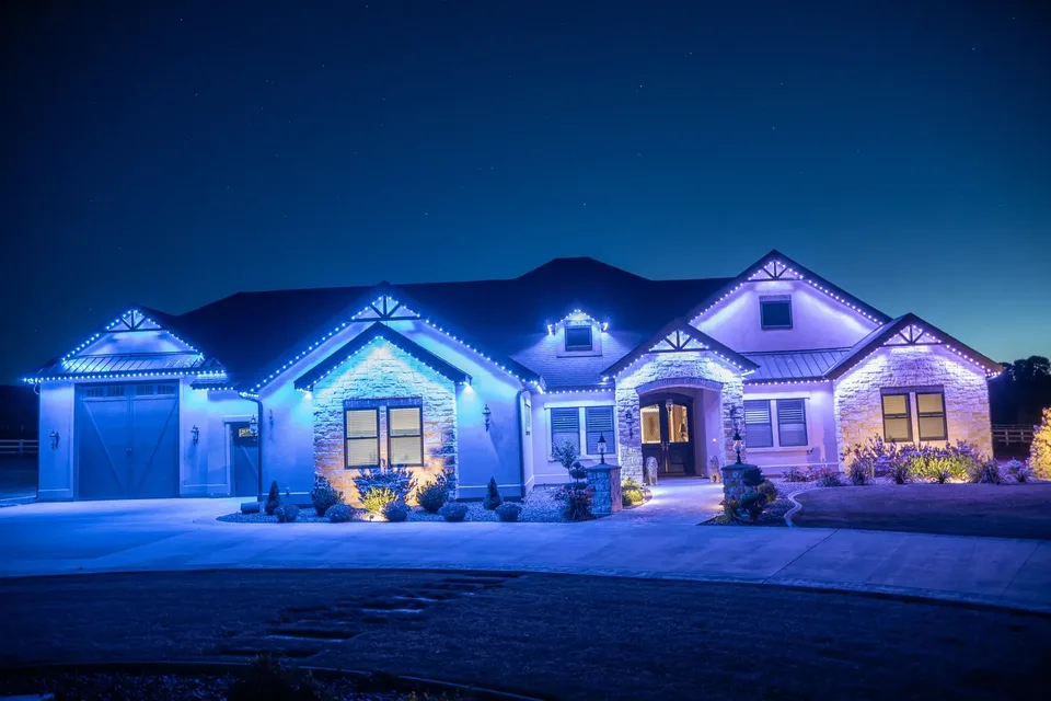 One blue held the whole way along every eave, gable and rake of the same ranch, the stone washed blue and the entry glowing warm through the door.