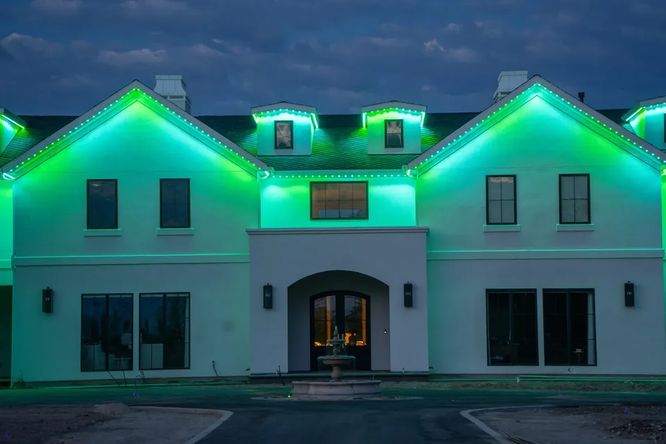 Green and teal on a white stucco two story, with white points still picking out the roofline.