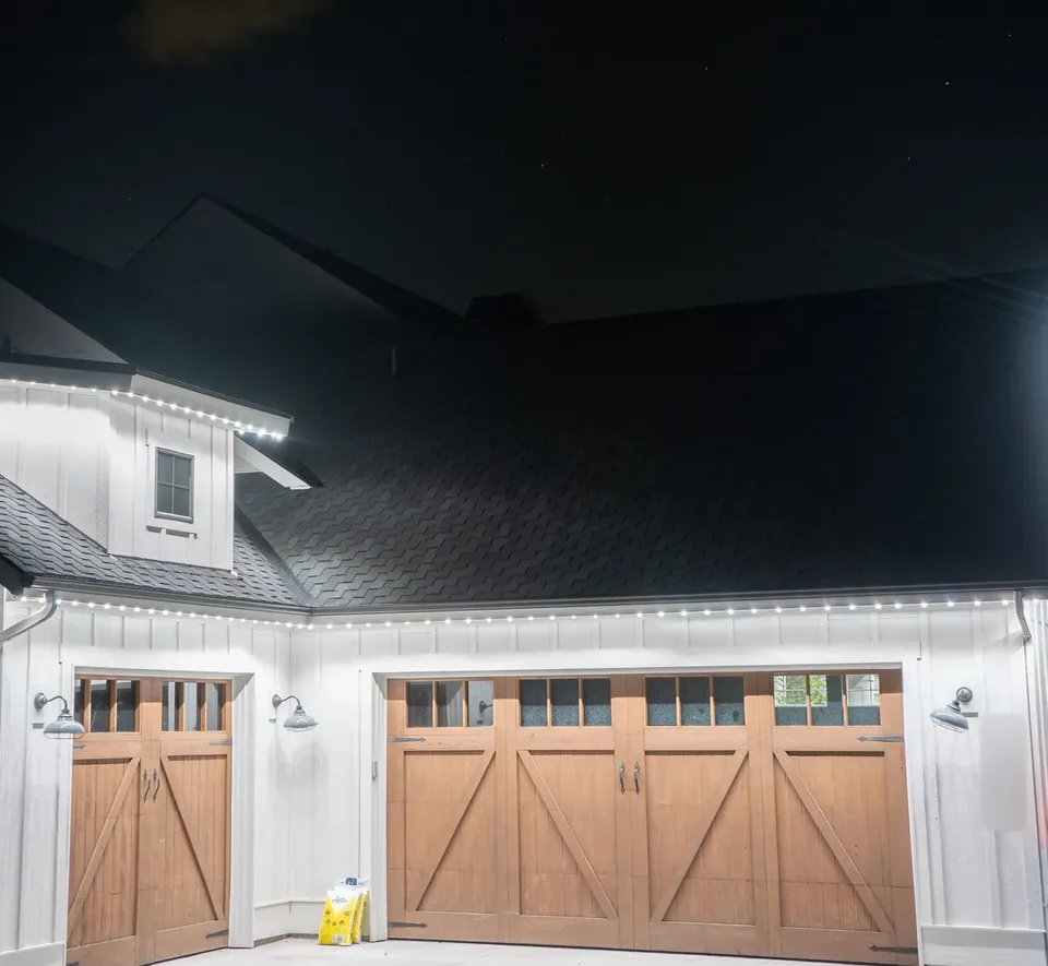Cool white along the eave of a board and batten garage, straight above the wood carriage doors.