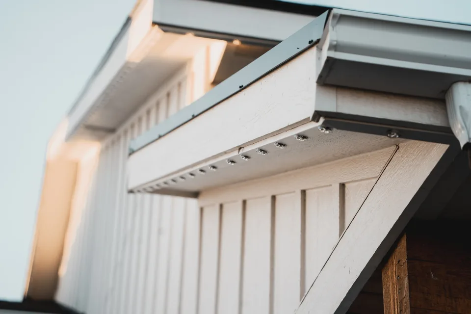 The underside of an eave in daylight, with the slim channel fitted along it and the points inside unlit.
