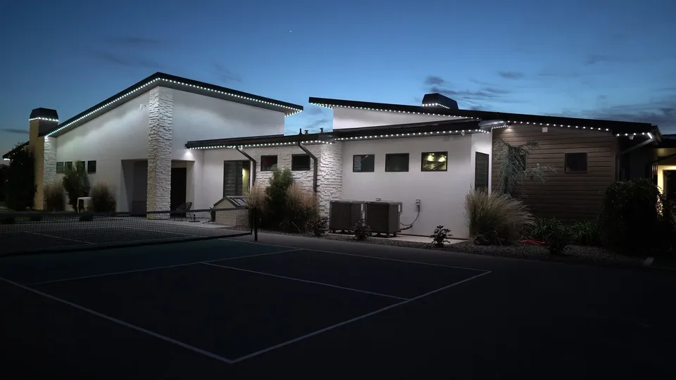 A modern ranch in cool white, seen across the sport court beside it.