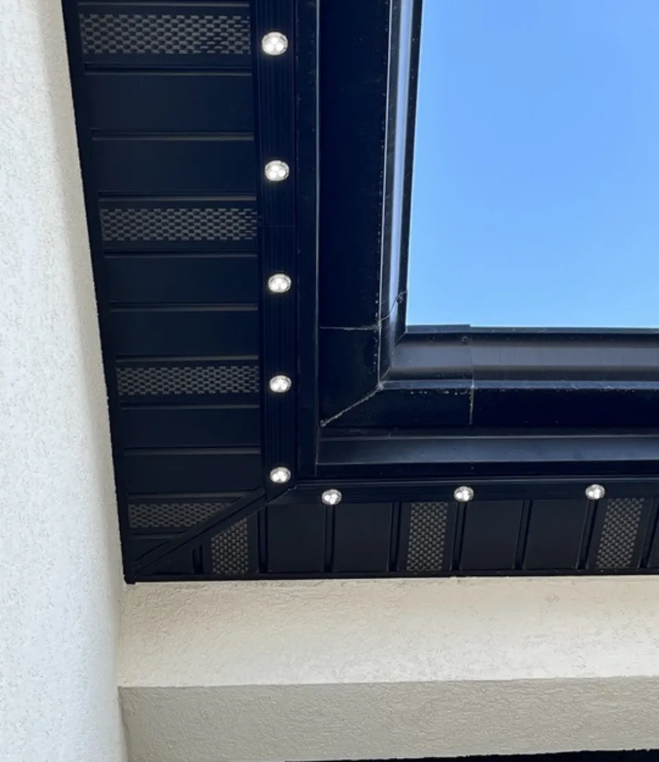 Channel in a dark bronze finish fitted against a dark soffit and roof edge, close up in daylight.