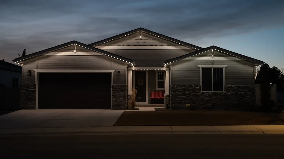 A single story house after dark, the whole roofline holding an even warm white.
